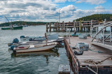 New England Rıhtımındaki küçük ıstakoz tekneleri: Sandıkları tutan ıstakozlar suda ve küçük balıkçı teknelerinin bulutlu bir öğleden sonra Maine 'de bağlandığı yüzen bir rıhtımda otururlar..