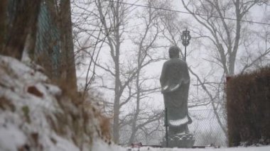 Buddhist Monk Statue in Heavy Snowfall, Back View, Low Angle, Wide shot. High quality 4k footage