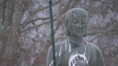 Buddhist Monk Statue in Heavy Snowfall, Buddhism in Winter Season, Medium shot. High quality 4k footage