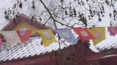 Waving Prayer Flags in Winter Weather, Buddhist Temple in Background, Close up. High quality 4k footage