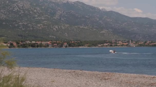 クロアチアの山の背景を持つダルマチア海岸のビーチとモーターボート 高品質4K映像 — ストック動画