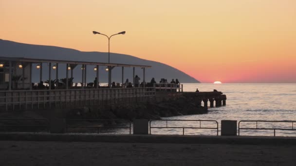 Ludzie Cieszący Się Zachodem Słońca Molo Restauracja Słońce Znikają Morzu — Wideo stockowe