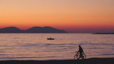 Golden Sunset plajında Bisiklet Yürüyen Kişi, yalnız başına sakin bir zaman sahnesi. Yüksek kalite 4k görüntü