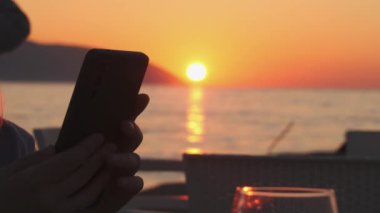 Seaside Sunset 'teki Resaturant' ta akıllı telefondan dijital dikkat dağıtma sahnesinde. Yüksek kalite 4k görüntü