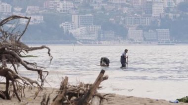 Vlora, Arnavut- 27 Nisan 2023: İki balıkçı denizden midye veya kabuklu deniz hayvanı topluyor. Yüksek kalite 4k görüntü