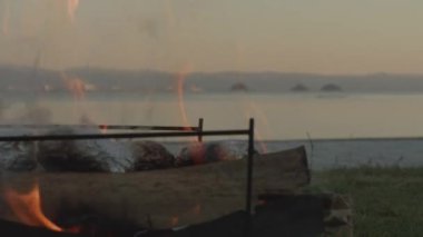 Dusk, Seascape ve Horizon 'daki Lakeside Kamp Ateşi Alevleri. Yüksek kalite 4k görüntü