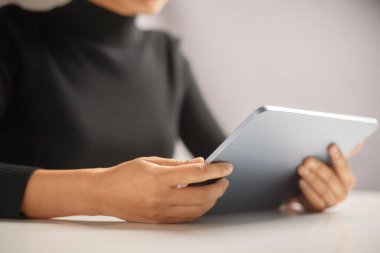 Basılı kitap yerine yazıyı okumak için tablet kullanan kadın elinin kapatılması.