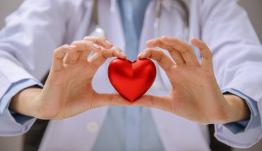 Kalbi kırmızı kalbi tutan doktor ya da doktorun kalp şeklinde eli. Bir tıp uzmanının kalp sağlığı konsepti.