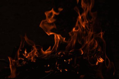 Karanlıkta alevler, karanlık arka planda parlak bir ateş.