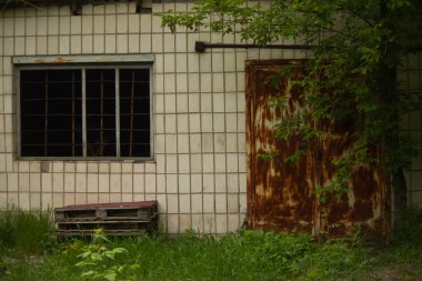 Eski terk edilmiş bina, kırık pencere ve paslı metal kapı.