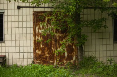 Eski terk edilmiş bina, kırık pencere ve paslı metal kapı.