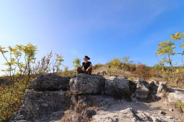 Parlak güneş ve mavi gökyüzünün altındaki büyük taşlar arasında meditasyon.