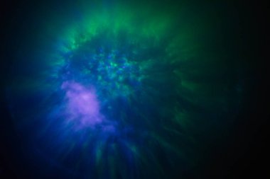 Kozmik renklerin büyüleyici bir görüntüsü, pembe, yeşil ve kırmızı renklerin parlak yıldızımsı noktalarla çevrili, uzaydaki bir nebulayı andıran canlı bir patlaması..