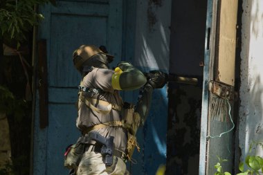 Tüfekli bir taktik asker terk edilmiş bir binaya girmeye hazırlanıyor. Açık hava operasyonunda hassasiyet ve odak gösteriyor.. 