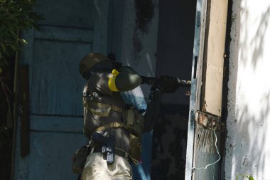 Tüfekli bir taktik asker terk edilmiş bir binaya girmeye hazırlanıyor. Açık hava operasyonunda hassasiyet ve odak gösteriyor.. 