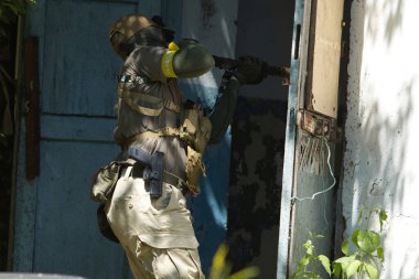 Tüfekli bir taktik asker terk edilmiş bir binaya girmeye hazırlanıyor. Açık hava operasyonunda hassasiyet ve odak gösteriyor.. 