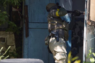 Tüfekli bir taktik asker terk edilmiş bir binaya girmeye hazırlanıyor. Açık hava operasyonunda hassasiyet ve odak gösteriyor.. 