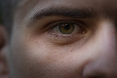 Doğal ışıkta büyüleyici bir fındık gözü olan bir insan gözünün yakın çekimi. Derinin detaylı dokusu ve kirpikleri görüntüye derinlik ve gerçekçilik ekler..