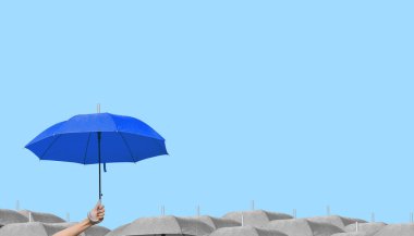 Mavi arka planda izole edilmiş gri şemsiyeler üzerinde koyu mavi bir şemsiye.. 