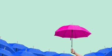 Adamın eli mor şemsiyeyi açık yeşil arka planda diğer mavi şemsiyelerin üzerinde tutuyor..