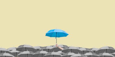 Sarı arka planda koyu renk şemsiyeler üzerine mavi şemsiye. İş dünyasına liderlik etmenin farkı, yağmurda elinde mavi şemsiye tutan bir adamın elidir. yan görünüm.