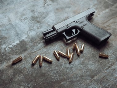 Arka planda cephanesi olan bir silah. 9 mm 'lik tabanca ve metal masada bir yığın mermi..