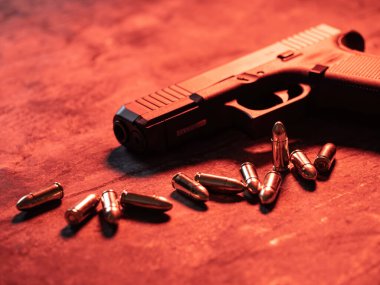 Arka planda cephanesi olan bir silah. 9 mm 'lik tabanca ve metal masada bir yığın mermi..