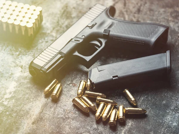 Hand gun with ammunition on dark background. 9 mm pistol military weapon with pile of bullets ammo and cartridge at the metal table.