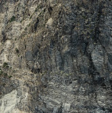 Yıpranmış deniz kenarındaki kaya yüzeyi dokusu. Yaşlanmış volkanik duvar yüzeyinin arka planında çatlaklar ve çizikler var. Ischia Adası, İtalya.