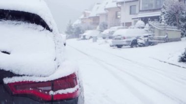 Şiddetli Kar Fırtınası Hareketi 'nin video kasedi. Rüzgarda düşen kar taneleri. Arka planda araba ve evler olan alçak alan ve cadde derinliği. Çeyrek hız.