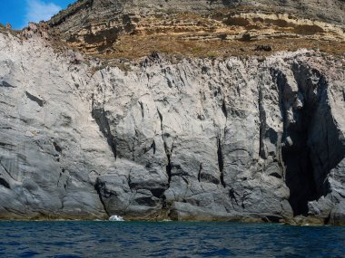 Yıpranmış deniz kenarındaki kaya yüzeyi dokusu. Yaşlanmış volkanik duvar yüzeyinin arka planında çatlaklar ve çizikler var. Ischia Adası, İtalya.