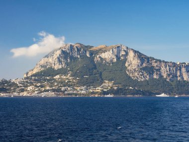 Yıpranmış deniz kenarı kaya yüzeyi dokusu ile yeşil ve mavi su parçaları. Yaşlanmış volkanik duvar yüzeyinin arka planında çatlaklar ve çizikler var. Solaro Dağı, Capri Adası, İtalya.