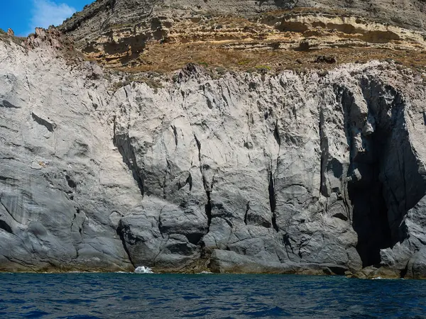 Yıpranmış deniz kenarındaki kaya yüzeyi dokusu. Yaşlanmış volkanik duvar yüzeyinin arka planında çatlaklar ve çizikler var. Ischia Adası, İtalya.