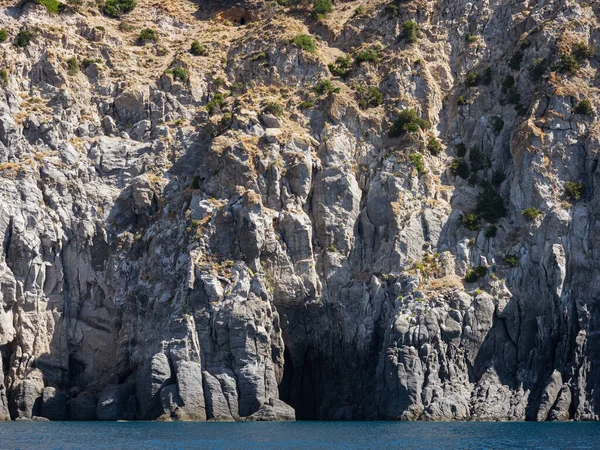 Yıpranmış deniz kenarındaki kaya yüzeyi dokusu. Yaşlanmış volkanik duvar yüzeyinin arka planında çatlaklar ve çizikler var. Ischia Adası, İtalya.