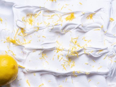 Dondurulmuş limon aromalı dondurma - tüm çerçeve ayrıntıları. Dondurmanın beyaz yüzey dokusunu kapatın. Sarı meyve parçalarıyla kaplı..