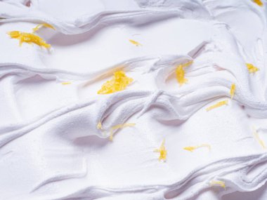 Dondurulmuş limon aromalı dondurma - tüm çerçeve ayrıntıları. Dondurmanın beyaz yüzey dokusunu kapatın. Sarı meyve parçalarıyla kaplı..