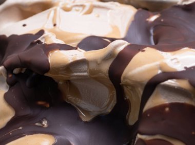 Dondurulmuş şekerleme aromalı dondurma - tüm çerçeve ayrıntıları. Karamel ve çikolata sosuyla kaplı bej kremalı dondurmanın yüzey dokusunu kapat..