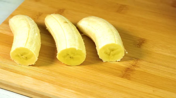 木のテーブルの上でバナナの切り身と皮をむいた — ストック写真