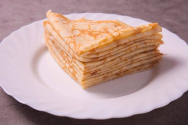 Gri arka planda tabakta bir yığın ince krep. Krep haftası