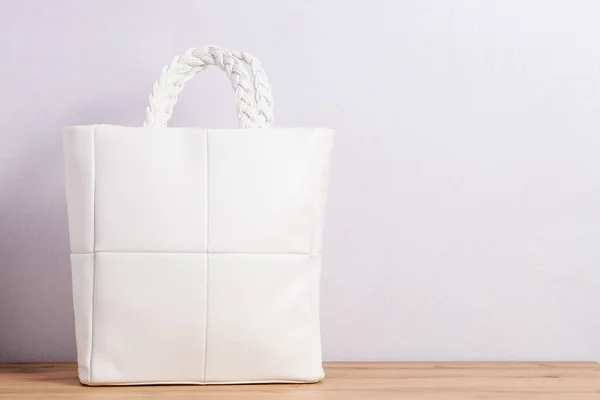 White leather shopper bag with braided handles on neutral background