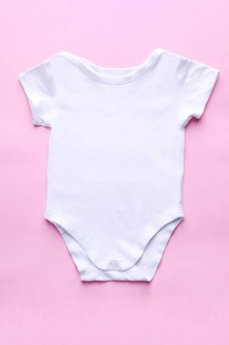 Pembe arka planda beyaz bebek kıyafeti.