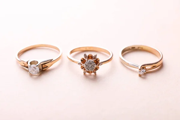 Három Gyűrű Sárga Fehér Arany Drágakövekkel Bézs Alapon — Stock Fotó