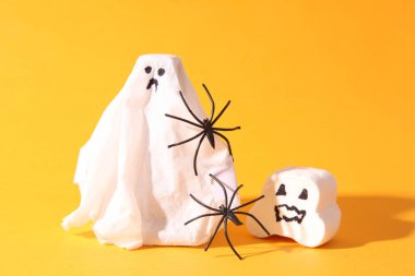 Turuncu arka planda örümcekleri olan beyaz hayaletler. Cadılar Bayramı konsepti