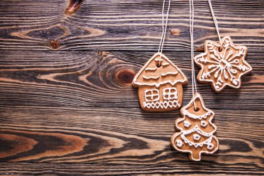 Farklı şekillerde zencefilli kurabiyeler, kahverengi ahşap arka planda kremayla süslenmiş..