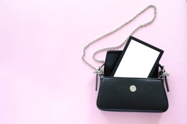 Pembe zincire bağlı siyah deri çanta içinde e-kitap..
