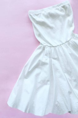 Pembe arka planda açık omuzlu beyaz çan elbisesi..