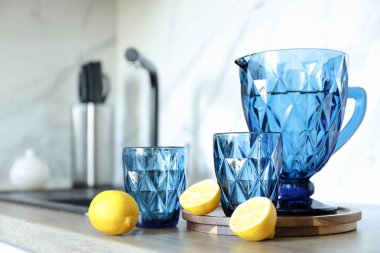 Mutfakta mavi yüzlü sürahi ve su ve limon dolu bardaklar..