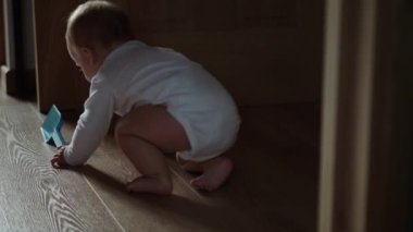 Mutlu erkek bebek emekleyerek yerde sürünüyor meraklı bebeğini keşfediyor çocukluğun tadını çıkarıyor. Beyaz elbiseli, gülümseyen küçük şirin çocuk ayağa kalkmaya çalış..