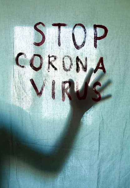 Stop Corona Virus inscription on a white sheet. Silhouette of the hand behind the sheet. Coronavirus (Covid-19) disease outbreak. Quarantine.