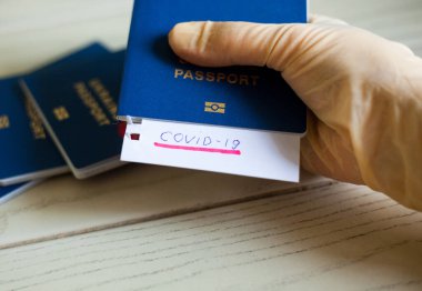 Eldivende Covid-19 'un pasaportu var. Coronavirus salgını. Salgın bir dönemde seyahat etmek. Pasaport sınır denetimi ve hasta turistlerin karantinası.